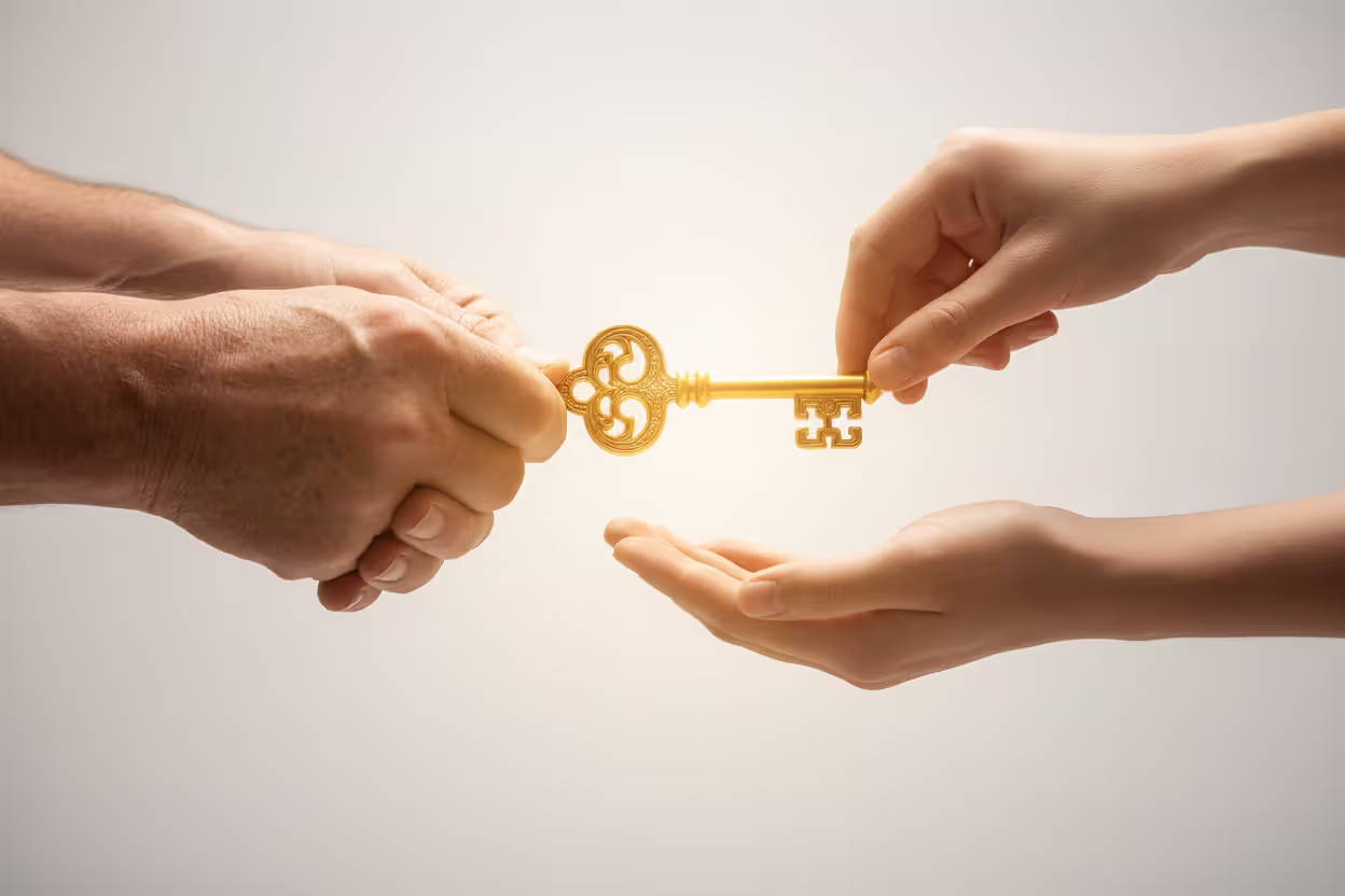 Elderly hands passing a golden key to younger hands symbolizing generational wealth transfer